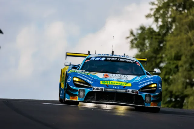 Blauer McLaren 720S GT3 über eine Kuppe, Wolkenhimmel im Hintergrund