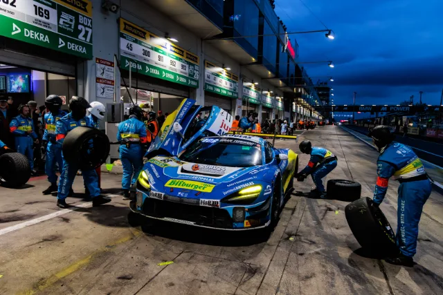 Boxenstopp in der blauen Stunde, Mechaniker wechseln die Reifen an einem blauen McLaren 720S GT3