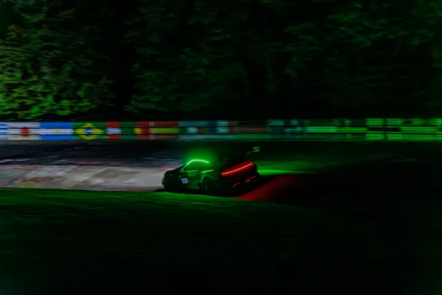 Nachtaufnahme im Mitzieher, Porsche 911 GT3 im grünen Licht am Streckenrand