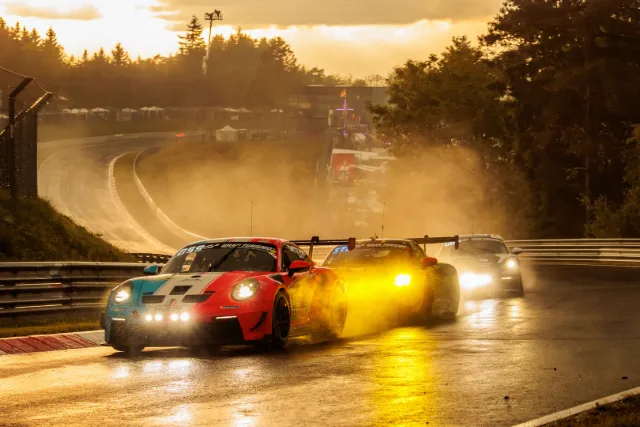 Porsche 911 GT3 Cup im Gischtnebel bei Sonnenuntergang, dahinter zwei weitere Fahrzeuge