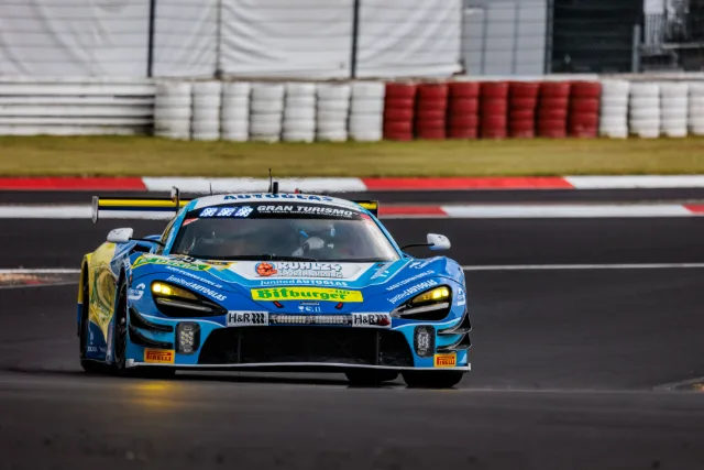 Blauer McLaren 720S GT3 in schneller Fahrt vor der Reifenstapel-Begrenzung