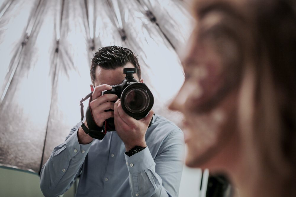 Patrick Liepertz beim Portraitshooting vor einem silbernen Studioschirm, die Kamera auf das Model im Vordergrund gerichtet
