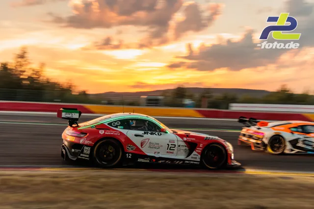 BMW M4 GT3 im Mitzieher bei Sonnenuntergang während der 24 Stunden von Spa-Francorchamps, dramatischer Himmel im Hintergrund.