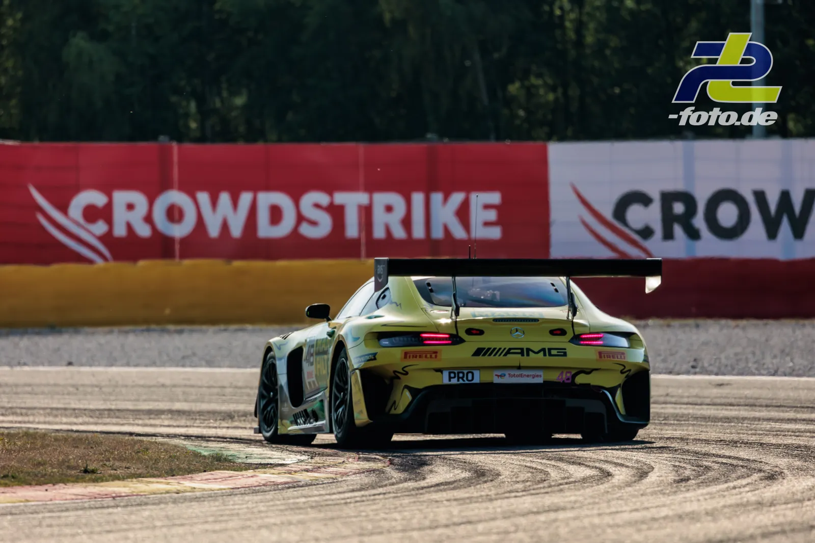 Mercedes-AMG GT3 EVO #48 in Kurve auf Auslaufzone, 24h Spa-Francorchamps, Heckansicht mit gelbem Farbschema und pinken Akzenten.