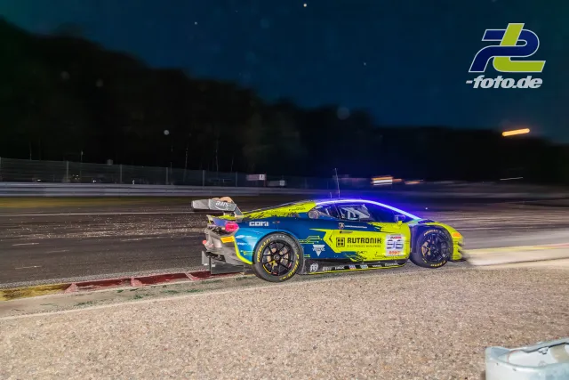 Lamborghini Temerario GT3 #96 von Rutronik Racing bei den 24 Stunden von Spa, nachts in der Auslaufzone mit Bergen im Hintergrund.