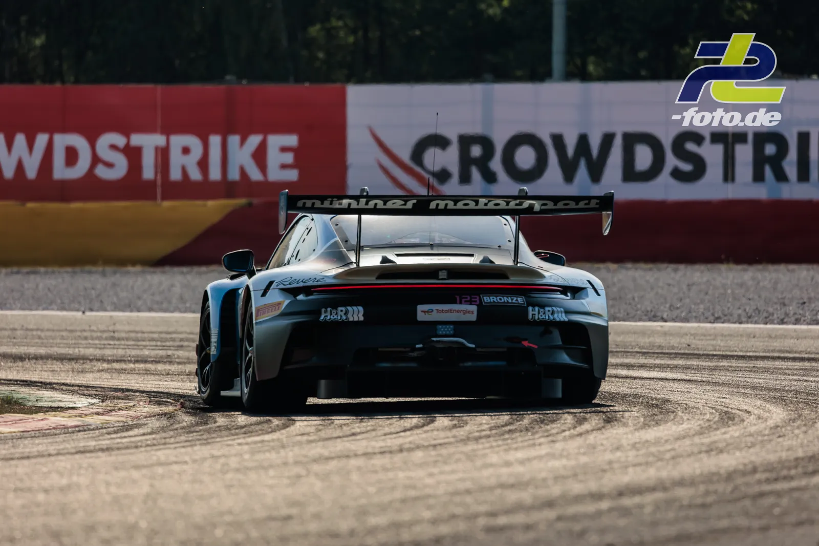 Porsche 911 GT3 R im Kiesbett in Spa-Francorchamps beim CrowdStrike 24 Hours of Spa, Heckansicht des hellblauen Fahrzeugs mit Heckspoiler.