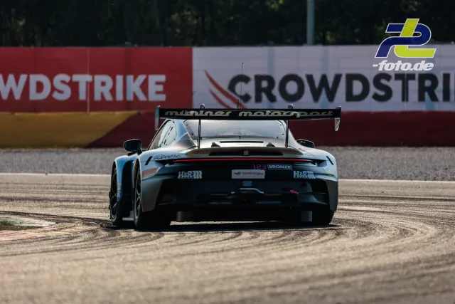 Porsche 911 GT3 R im Kiesbett in Spa-Francorchamps beim CrowdStrike 24 Hours of Spa, Heckansicht des hellblauen Fahrzeugs mit Heckspoiler.