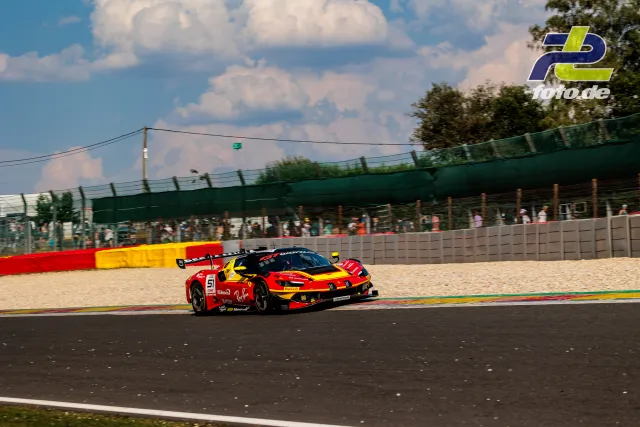 Ferrari 296 GT3 EVO von AF Corse in einer Kurve beim 24-Stunden-Rennen von Spa-Francorchamps, Kiesbett und Zuschauer im Hintergrund.