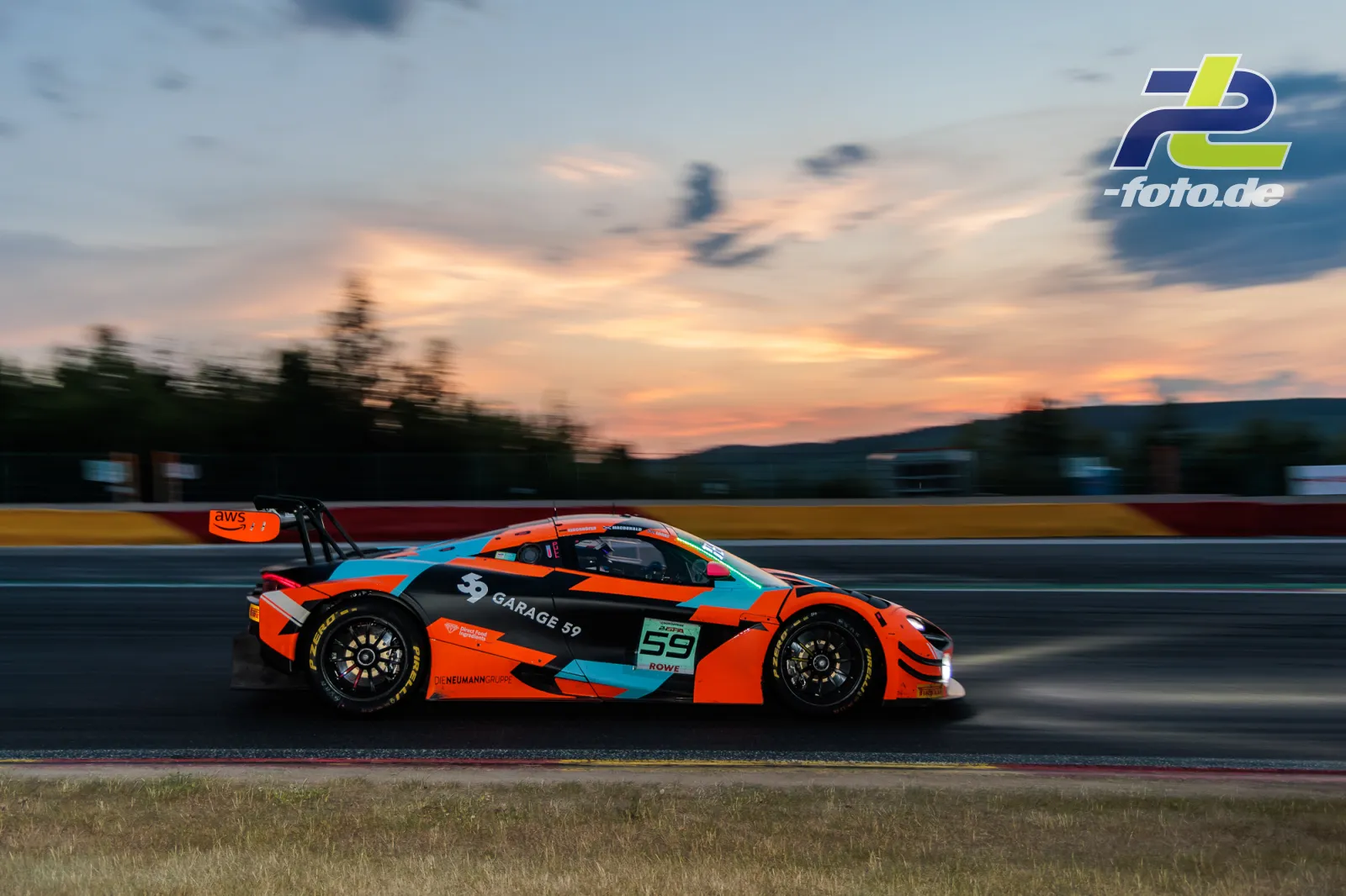 McLaren 720S GT3 EVO Nummer 59 von Garage 59 in der Dämmerung beim 24-Stunden-Rennen von Spa-Francorchamps, Mitzieher in Orange und Türkis.