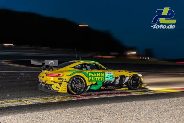 Mercedes-AMG GT3 EVO in gelb-grüner Lackierung bei den 24 Stunden von Spa-Francorchamps während der Dämmerung auf der Strecke.