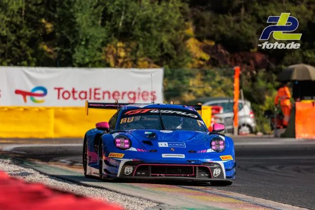 Blau-pinker Porsche 911 GT3 R auf der Strecke in Spa-Francorchamps beim 24-Stunden-Rennen, Randstein und Kiesbett neben dem Fahrzeug.