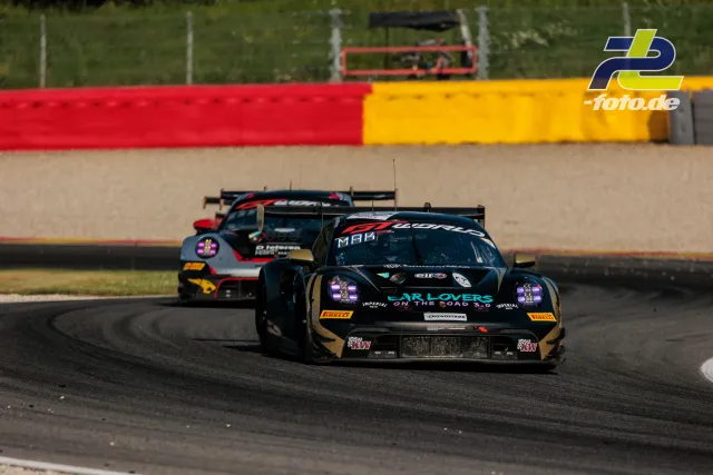 Porsche 911 GT3 R (992) EVO Nr. 22 in Kurve vor Verfolgerfahrzeug beim 24-Stunden-Rennen von Spa-Francorchamps mit bunten Streckenbegrenzungen.