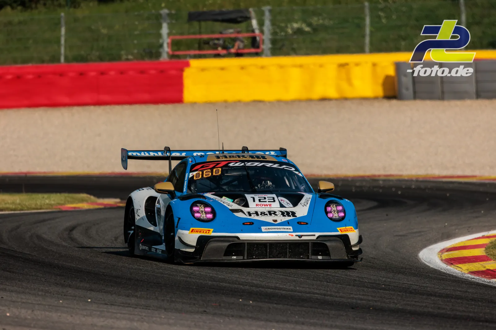 Porsche 911 GT3 R in der Kurve beim 24-Stunden-Rennen von Spa-Francorchamps, mit charakteristischer rot-gelber Streckenbegrenzung.