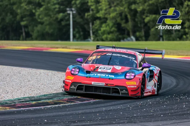 Porsche 911 GT3 R in rot-türkiser Lackierung beim 24-Stunden-Rennen von Spa-Francorchamps in der Kurve auf der Rennstrecke.