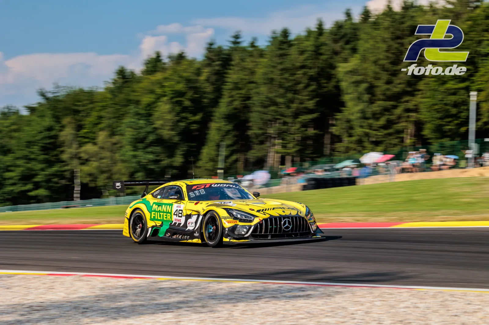Gelber Mercedes-AMG GT3 EVO #48 in Fahrt auf der Rennstrecke beim 24-Stunden-Rennen von Spa-Francorchamps, Mitzieher mit Waldhintergrund.