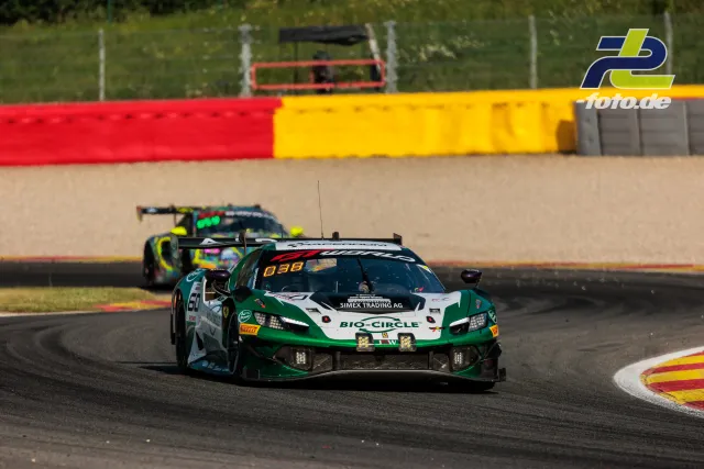 Ferrari 296 GT3 EVO #60 von JMW Motorsport in Kurve bei den 24 Stunden von Spa-Francorchamps, mit farbigen Streckenbegrenzungen im Hintergrund.