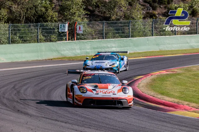 Porsche 911 GT3 R in orange-weißer Ziggo-Lackierung führt ein Verfolgerduell in einer Kurve beim 24-Stunden-Rennen von Spa-Francorchamps an.