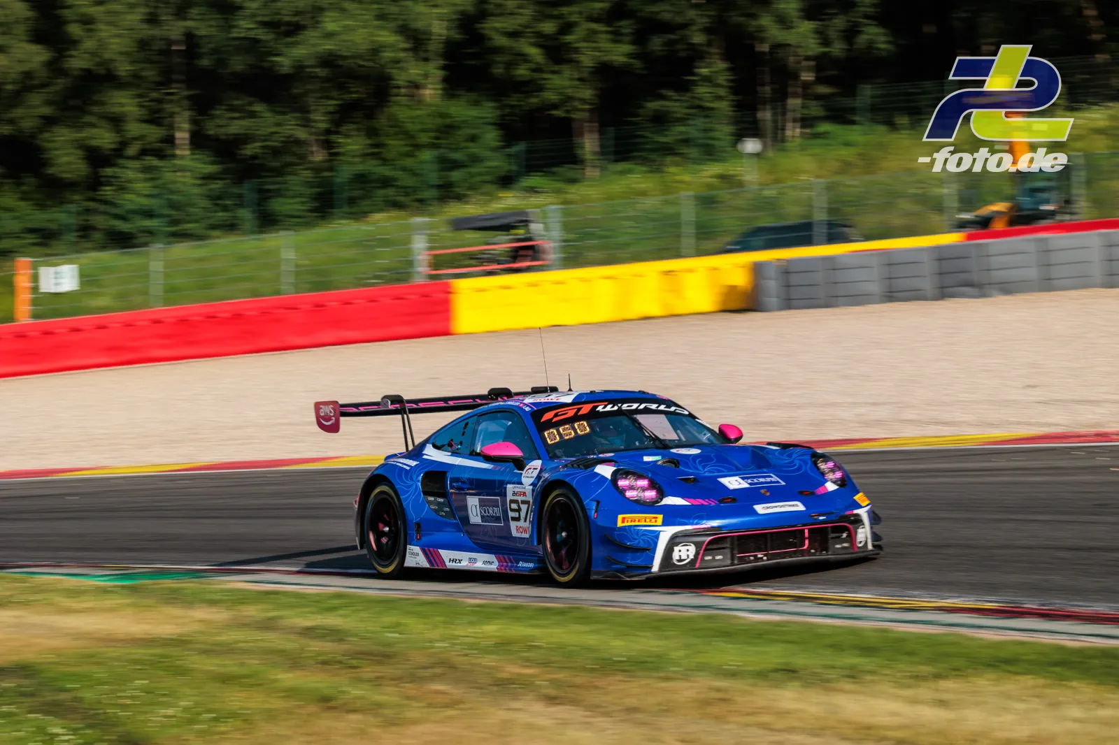 Porsche 911 GT3 R (992) EVO von Rutronik Racing in Kurve bei 24h Spa-Francorchamps, blaue Lackierung mit pinkfarbenen Akzenten.