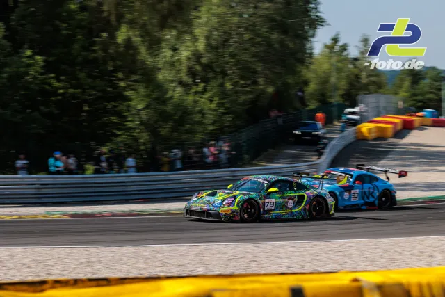 Porsche 911 GT3 R mit bunter Lackierung auf der Strecke in Spa-Francorchamps beim 24-Stunden-Rennen, gefolgt von einem blauen Fahrzeug.