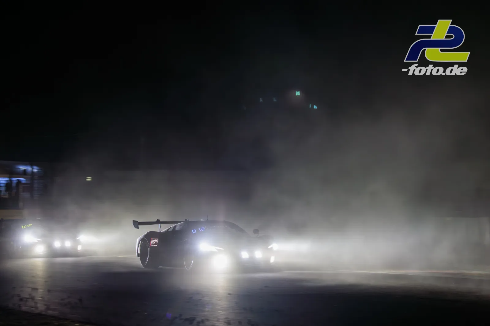 Ferrari 296 GT3 EVO #52 von AF Corse bei Nacht im dichten Nebel während der 24 Stunden von Spa-Francorchamps mit eingeschalteten Scheinwerfern.