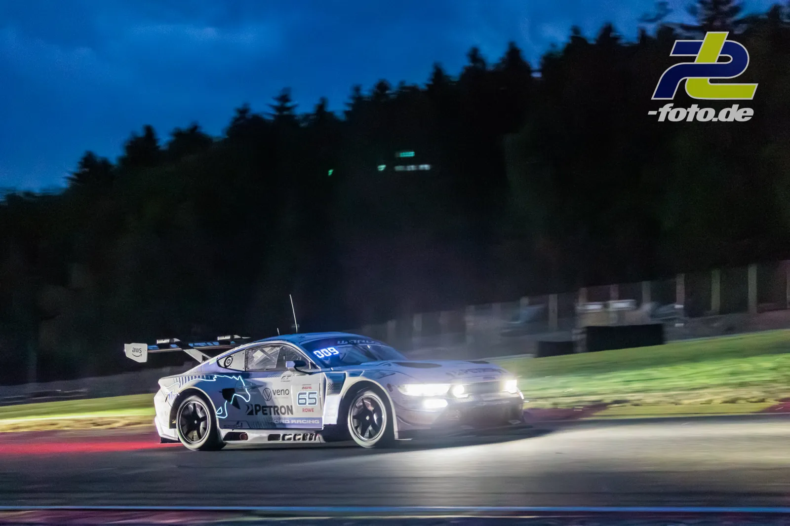 Porsche 911 GT3 R bei Nacht mit eingeschalteten Scheinwerfern auf der Strecke in Spa-Francorchamps während der 24 Stunden von Spa.