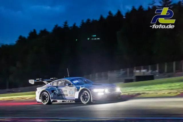 Porsche 911 GT3 R bei Nacht mit eingeschalteten Scheinwerfern auf der Strecke in Spa-Francorchamps während der 24 Stunden von Spa.