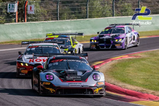 Porsche 911 GT3 R führt eine Fahrzeuggruppe durch eine Kurve beim 24-Stunden-Rennen von Spa-Francorchamps, Randsteine im Vordergrund