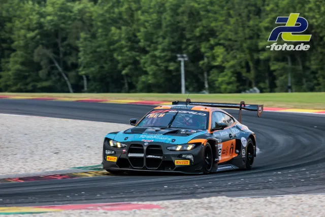 BMW M4 GT3 EVO in der Kurve beim 24-Stunden-Rennen von Spa-Francorchamps, türkis-orange Lackierung, Randsteine im Hintergrund