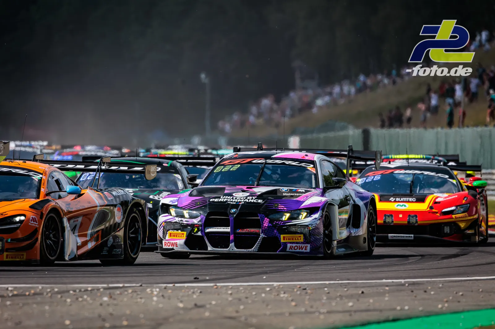 Dichtes Fahrerfeld beim Start des 24-Stunden-Rennens von Spa-Francorchamps mit Zuschauern auf der Tribüne