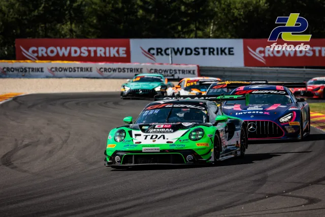 Grüner Porsche 911 GT3 R führt Fahrzeugfeld durch eine Kurve beim 24-Stunden-Rennen von Spa-Francorchamps.