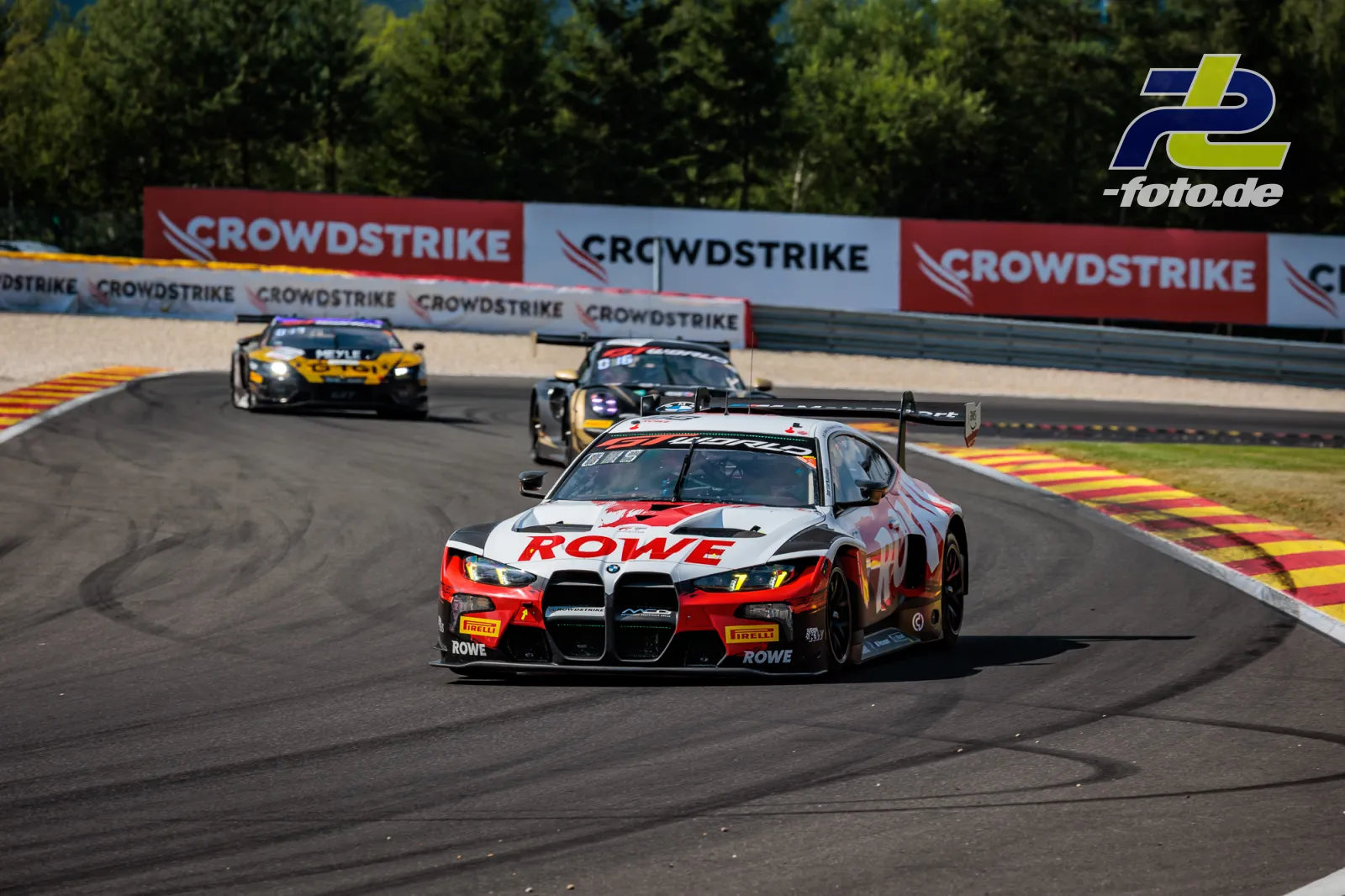 BMW M4 GT3 EVO von Rowe Racing führt durch Kurve beim 24-Stunden-Rennen Spa-Francorchamps, gefolgt von zwei Konkurrenten.