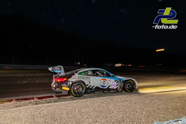 BMW M4 GT3 EVO des Team WRT fährt nachts in Spa-Francorchamps über ein Kiesbett neben der Strecke.