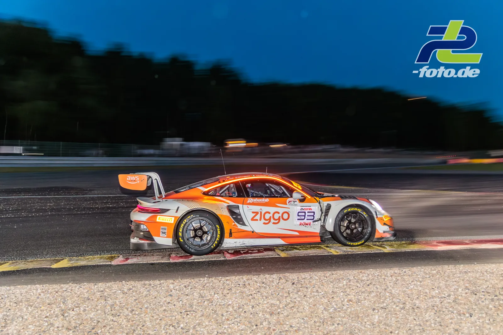 Porsche 911 GT3 R beim 24-Stunden-Rennen von Spa-Francorchamps in der Dämmerung, Seitenansicht an der Randsteinbegrenzung.