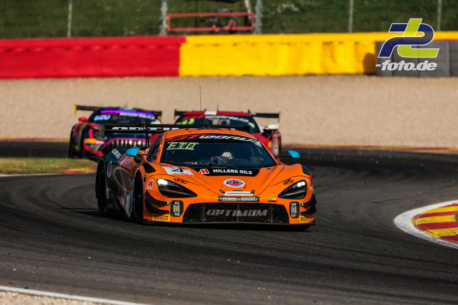 McLaren 720S GT3 EVO in Orange führt eine Gruppe von GT3-Fahrzeugen durch eine Kurve in Spa-Francorchamps beim 24-Stunden-Rennen.