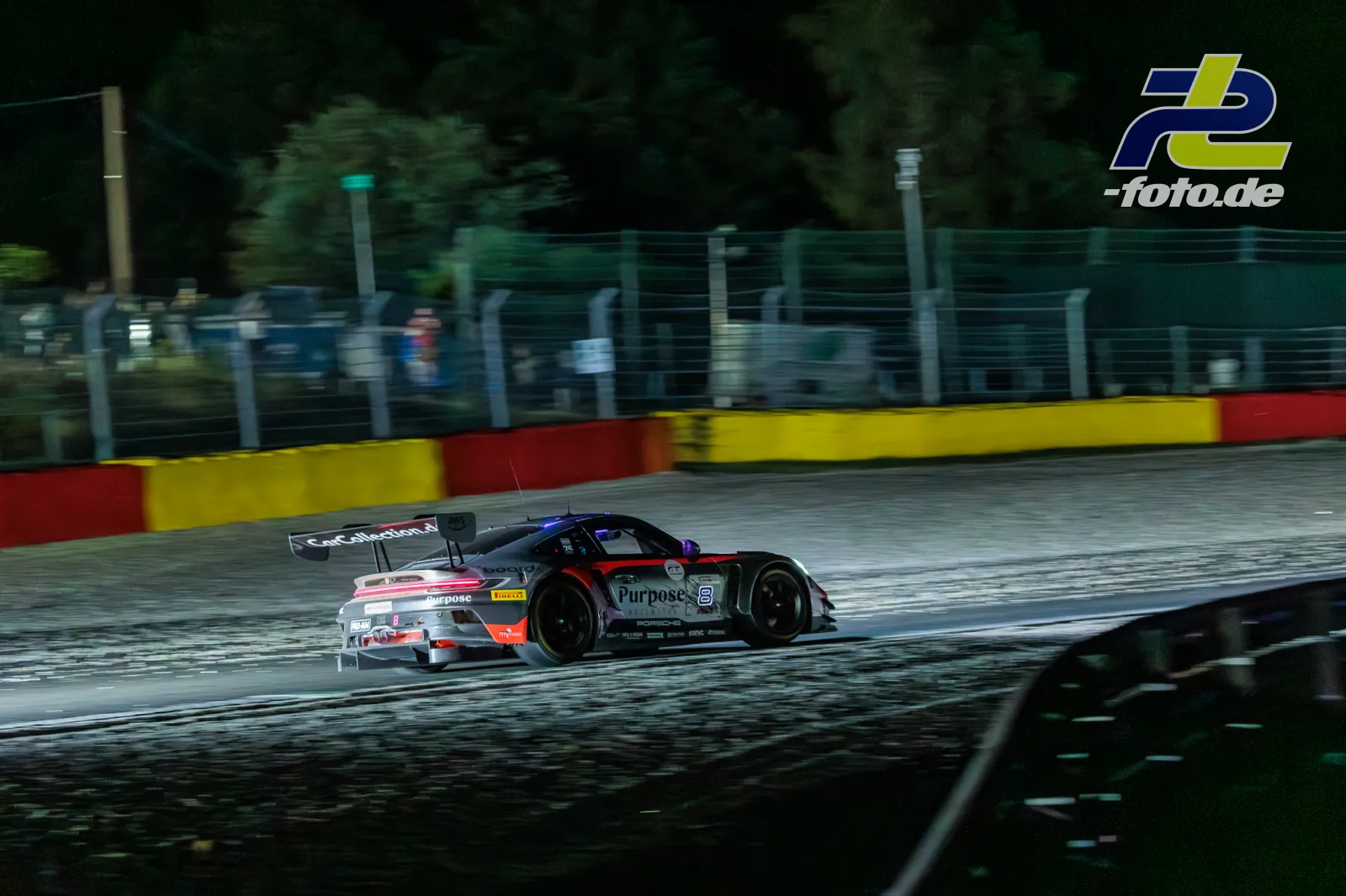 Porsche 911 GT3 R mit Startnummer 8 auf nasser Strecke beim 24h-Rennen Spa-Francorchamps, Mitzieher-Aufnahme mit Bewegungsunschärfe.