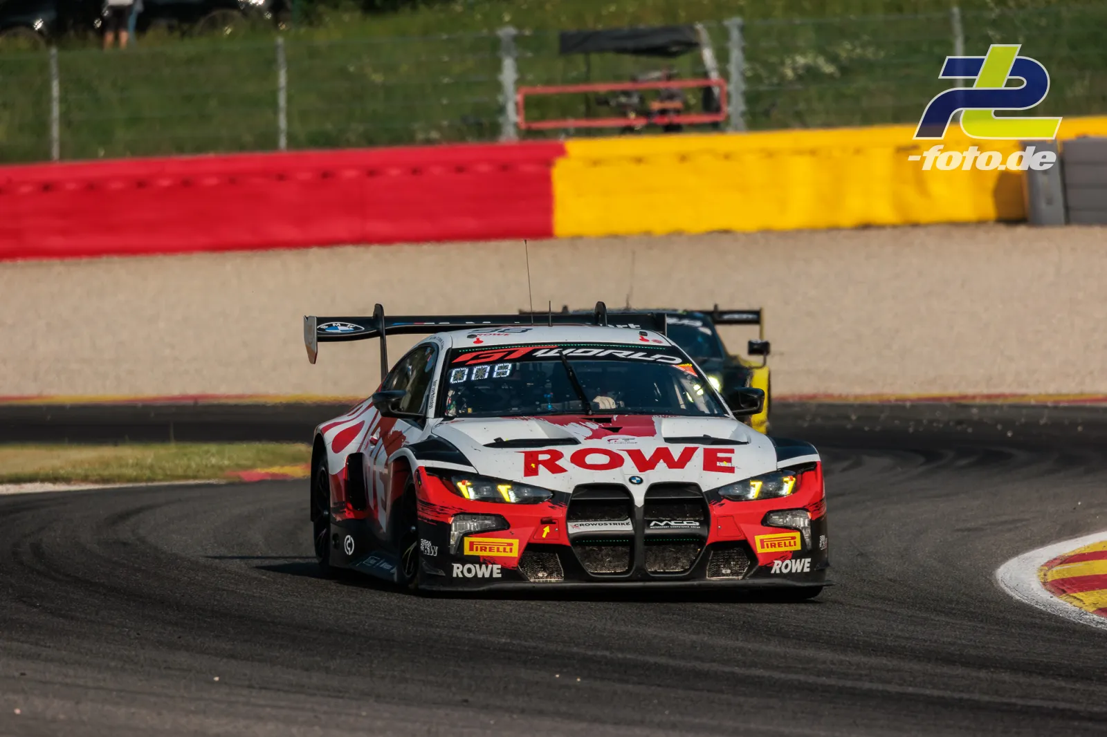 BMW M4 GT3 EVO von Rowe Racing beim 24-Stunden-Rennen von Spa-Francorchamps in einer Kurve mit rot-gelber Streckenbegrenzung.