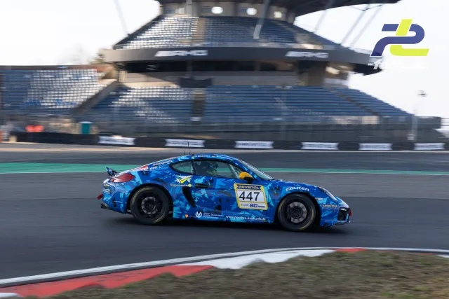 Porsche Cayman GT4 mit Startnummer 447 in blauer Camouflage-Lackierung auf dem Nürburgring während des Zeittrainings.