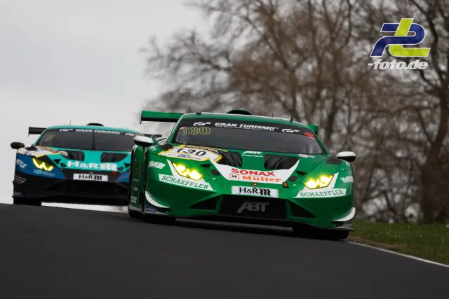 Zwei GT-Fahrzeuge mit Licht bei bedecktem Wetter auf der Nordschleife, vorne ein grüner, dahinter ein türkis-blauer Rennwagen.