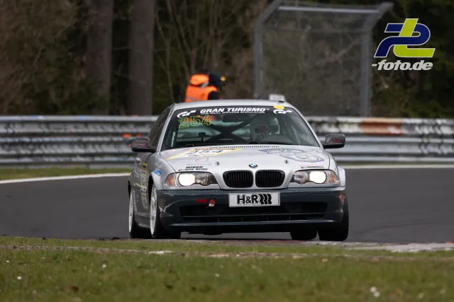 Weißer BMW E46 #254 im Rennen auf dem Nürburgring, im Hintergrund Streckenposten in orange.