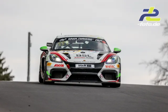 Porsche 718 Cayman GT4 Nr. 171 in weißer AVIA-Lackierung über eine Kuppe auf dem Nürburgring während des NLS-Rennens.