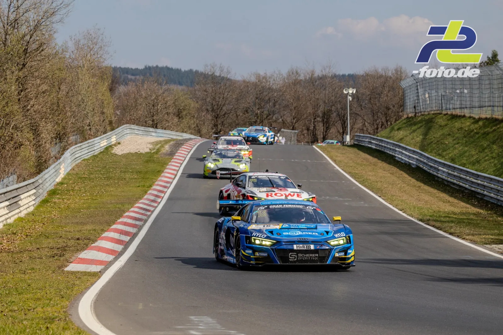 Rennszene auf der Nordschleife mit mehreren GT-Fahrzeugen auf einer Bergauf-Passage, angeführt von einem blauen Audi R8 LMS GT3 Evo II.