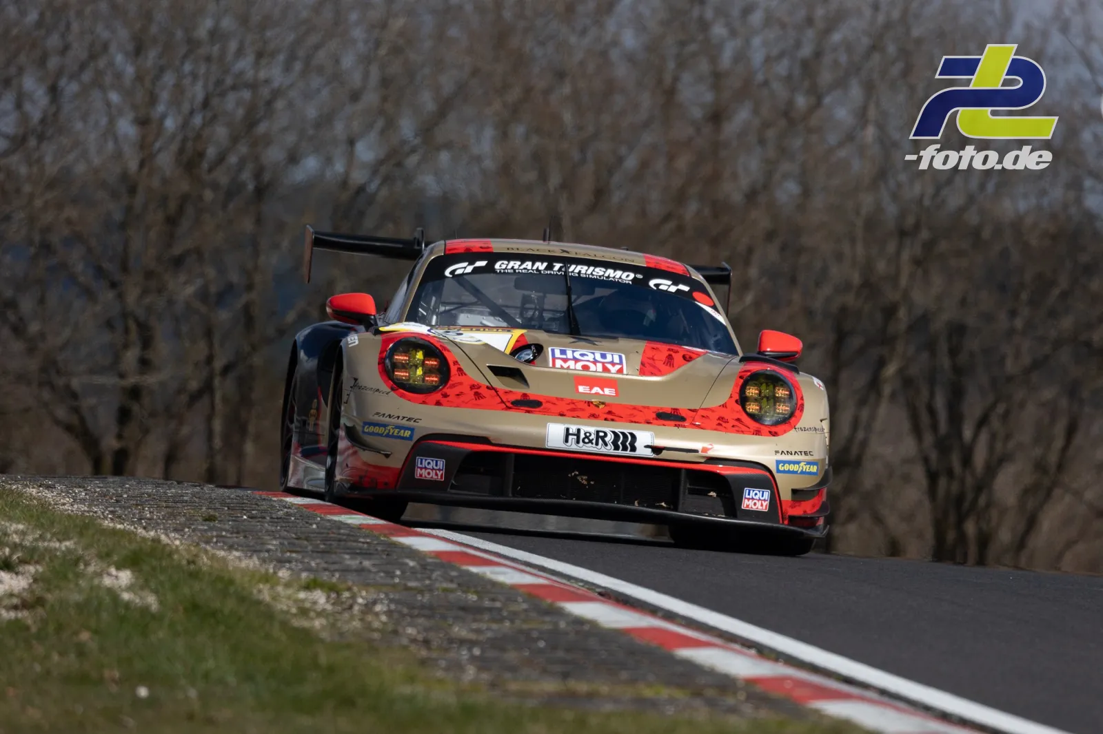 Porsche 911 GT3 R in beige-roter Lackierung auf der Kuppe einer Nordschleifen-Passage während des NLS-Rennens