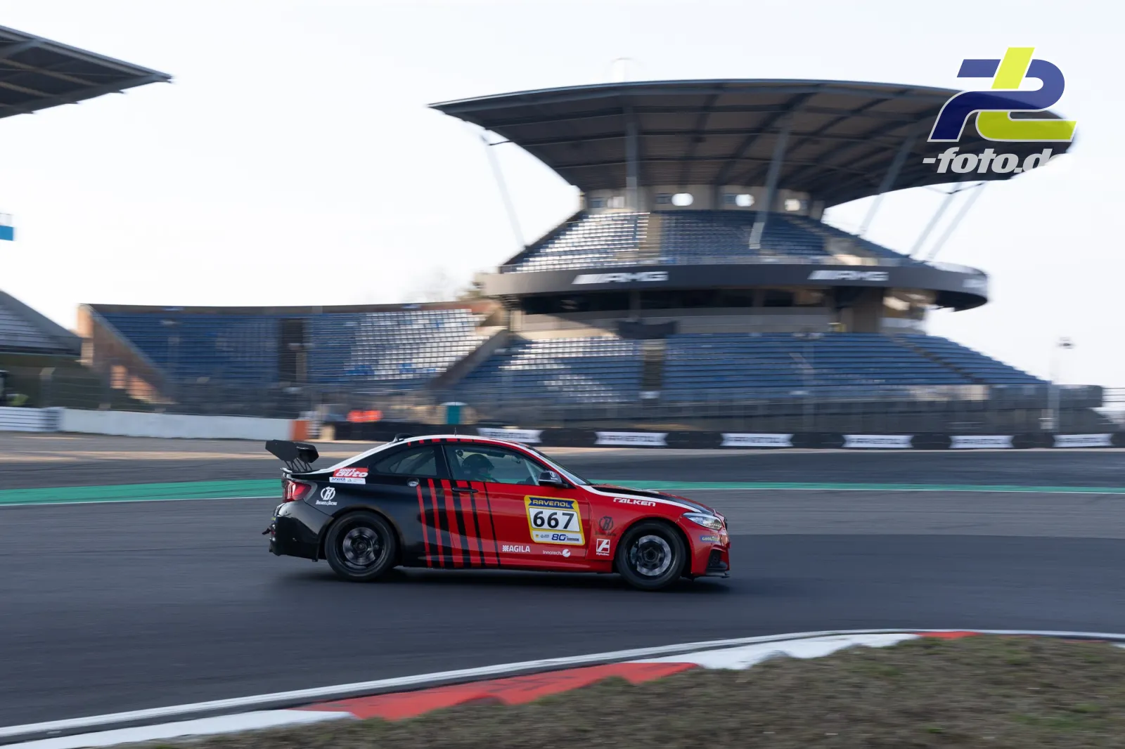 BMW mit roter Lackierung und schwarzen Streifen in Seitenansicht vor der Haupttribüne auf dem Nürburgring während des Zeittrainings.