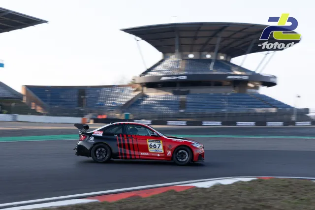 BMW mit roter Lackierung und schwarzen Streifen in Seitenansicht vor der Haupttribüne auf dem Nürburgring während des Zeittrainings.