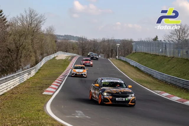 Fünf Fahrzeuge in einer Kuppe auf der Nürburgring-Nordschleife, angeführt von einem schwarz-orangen BMW.