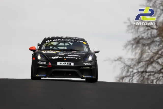Porsche Cayman GT4 mit Startnummer 978 von Krämer Racing auf Bergkuppe am Nürburgring-Nordschleife bei bewölktem Wetter.