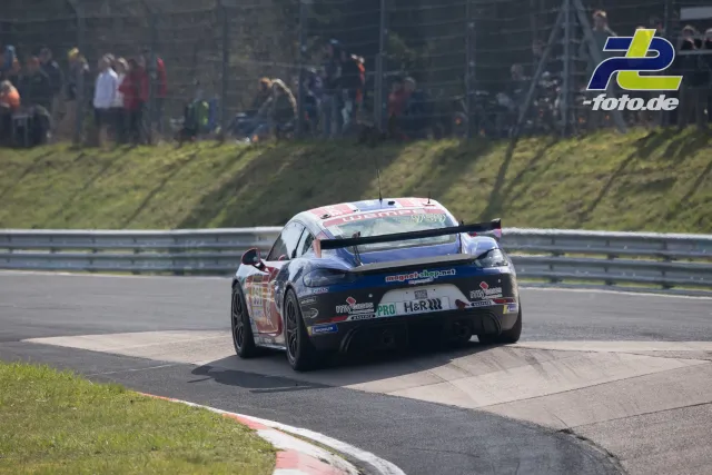 Porsche Cayman im Rennen auf dem Nürburgring, Heckansicht in Kurve mit Zuschauern hinter der Leitplanke