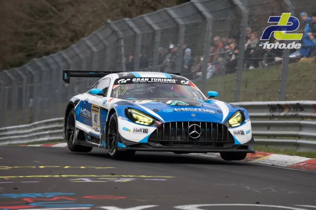 Mercedes-AMG GT3 #47 in weiß-blauer Lackierung auf der Nürburgring-Nordschleife während des NLS-Rennens, Zuschauer an der Strecke.