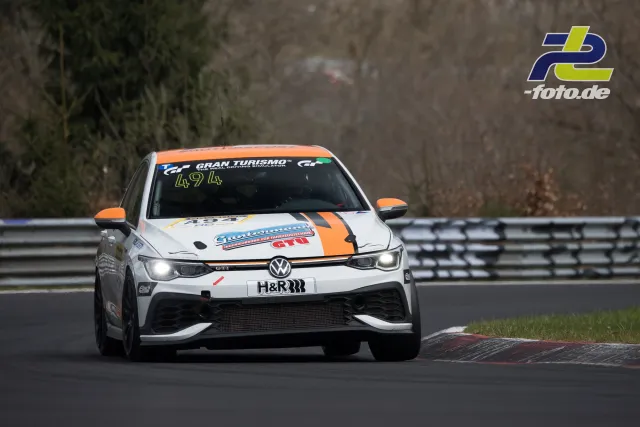 VW Golf GTI #494 im Rennen auf der Nordschleife, weißer Rennwagen mit oranger Lackierung und H&R-Kennzeichen