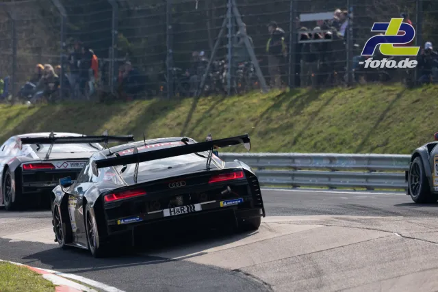 Mehrere GT3-Fahrzeuge in einer Rechtskurve, Zuschauer hinter dem Zaun, Nürburgring.